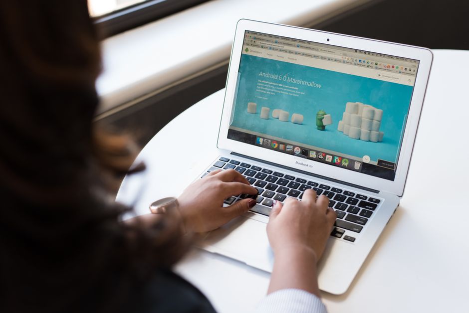 Femme d'affaires travaillant sur un ordinateur portable avec la page web d'Android 6.0 Marshmallow ouverte.