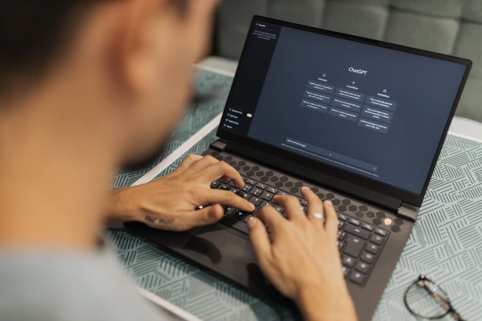 Personne concentrée tapant sur un ordinateur portable exécutant un logiciel d'IA en intérieur.