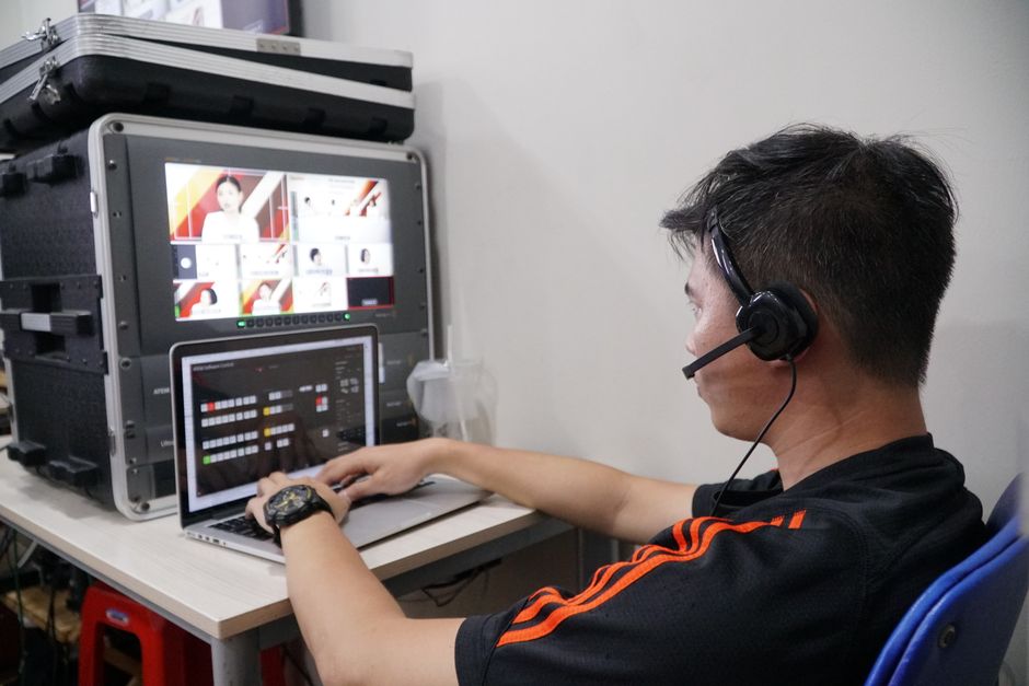 Technicien gérant plusieurs flux vidéo à l'aide d'un ordinateur portable et d'un écran dans un studio.