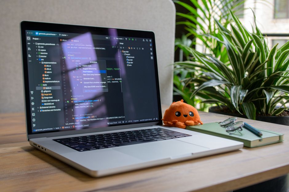 Un ordinateur portable avec une interface de programmation, une plante et un jouet pour une ambiance d'espace de travail chaleureuse.