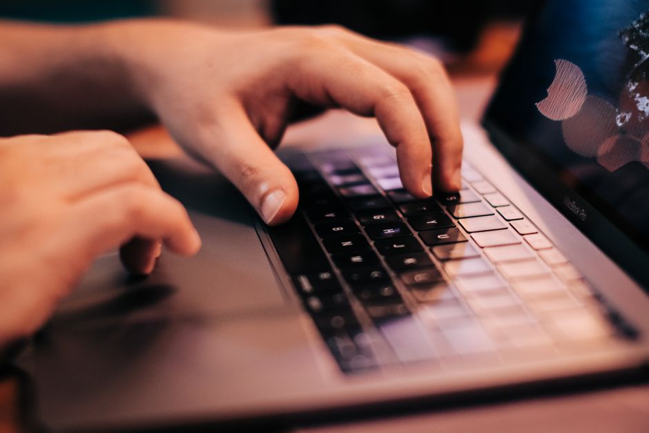 Vue rapprochée des mains d'une personne tapant sur le clavier d'un ordinateur portable.