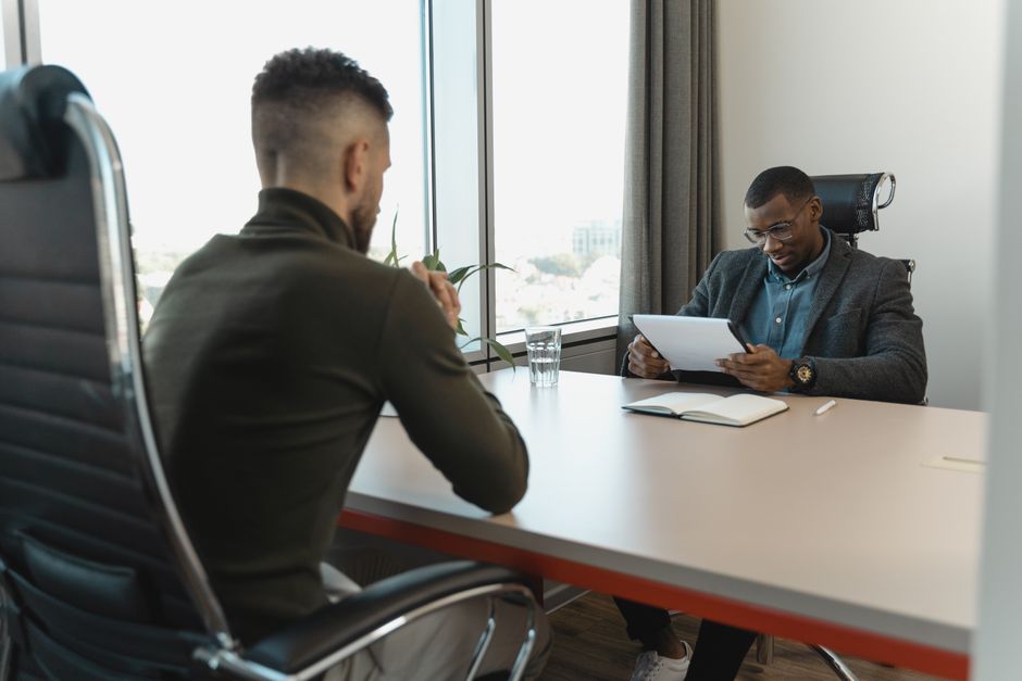 Entretien d'embauche entre deux hommes professionnels dans un bureau moderne.