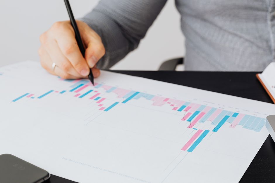 Gros plan sur un homme écrivant sur un graphique imprimé, analysant des données colorées en intérieur.