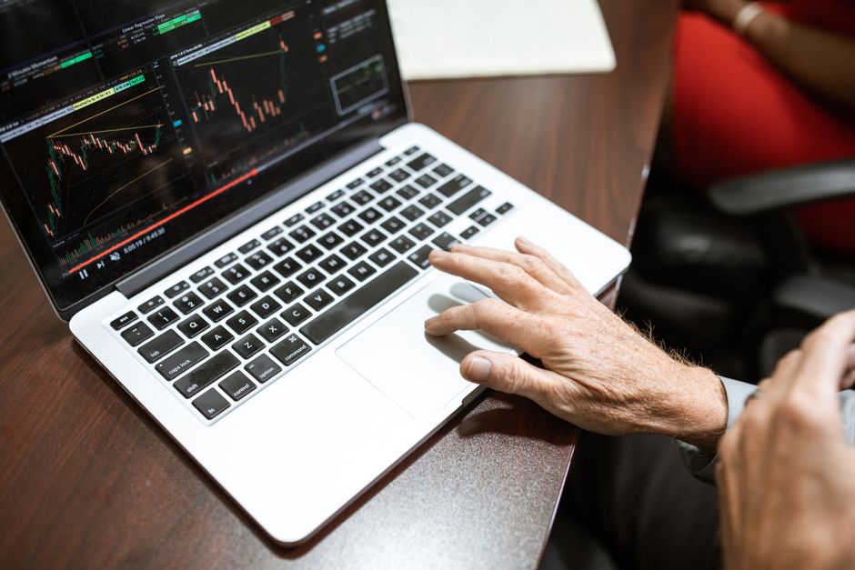 Gros plan sur une main utilisant un ordinateur portable pour l'analyse boursière dans un bureau.