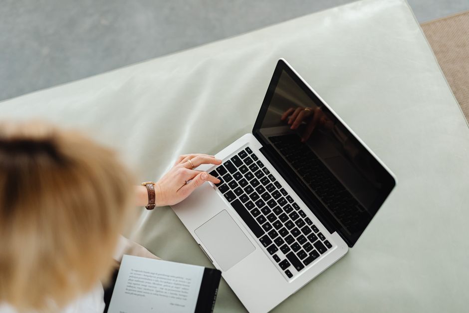 Une femme utilise un ordinateur portable en intérieur, illustrant le télétravail.