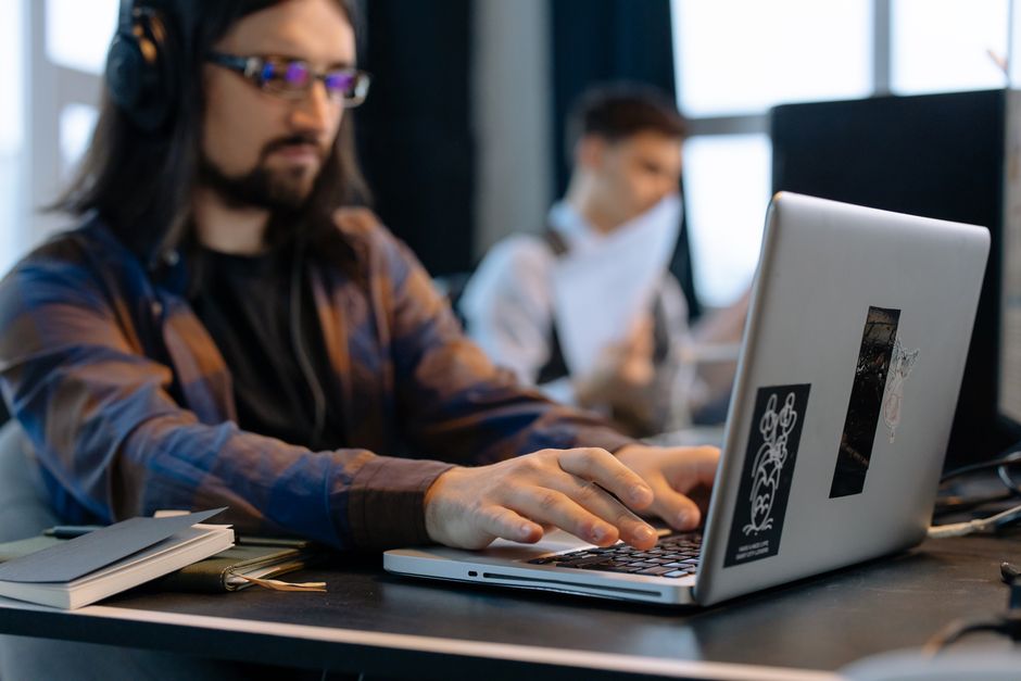 Homme portant un casque, concentré sur sa saisie au clavier dans un bureau contemporain.