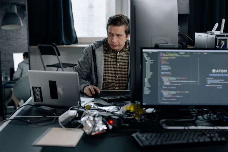 Programmeur dans un bureau moderne travaillant sur du code informatique, illustrant un environnement de travail concentré.
