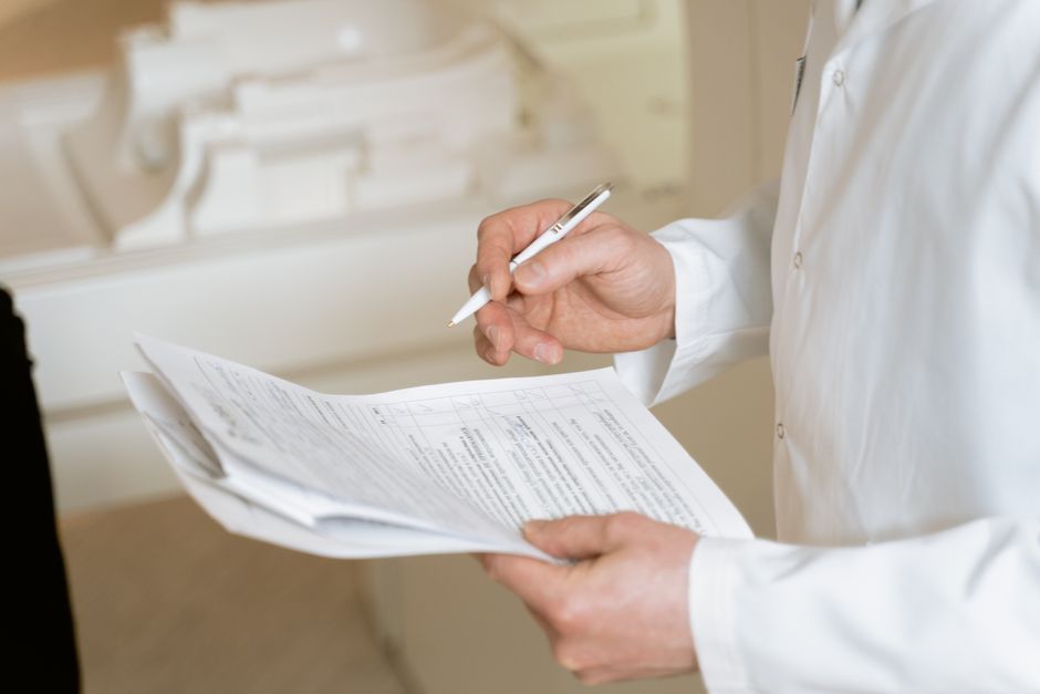 Un médecin tient et examine des documents médicaux, faisant preuve de rigueur et de professionnalisme.