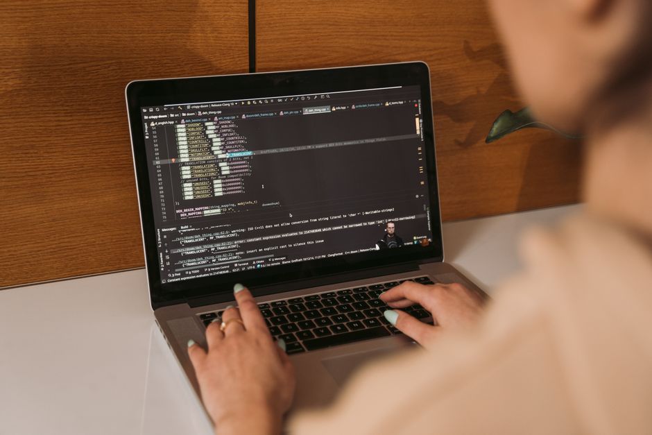 Gros plan d'une femme programmant sur un ordinateur portable dans un environnement de bureau, illustrant une technologie moderne.