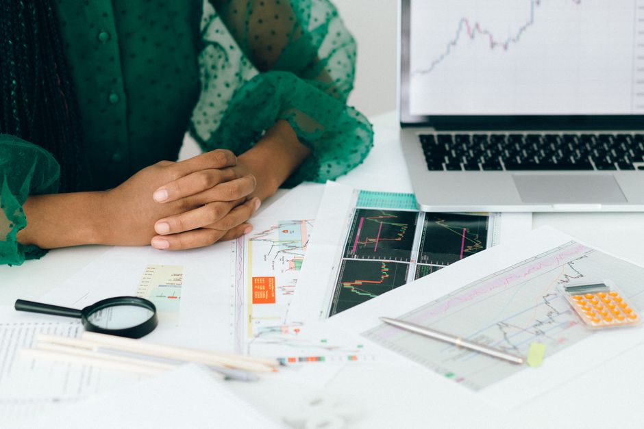 Personne analysant des graphiques financiers à un bureau, illustrant une activité de trading.