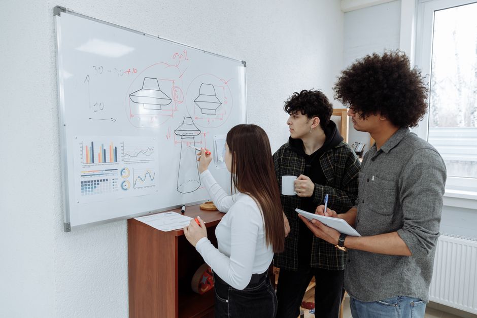 De jeunes professionnels faisant du brainstorming et concevant le prototype d'un produit sur un tableau blanc.