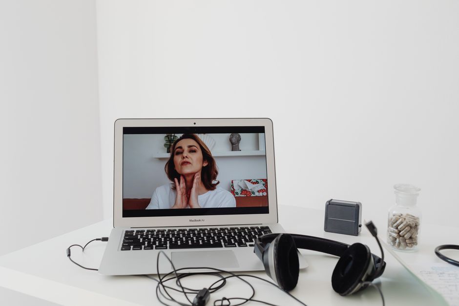 Femme menant une séance de télémédecine visible sur l'écran d'un ordinateur portable, avec un casque à proximité.