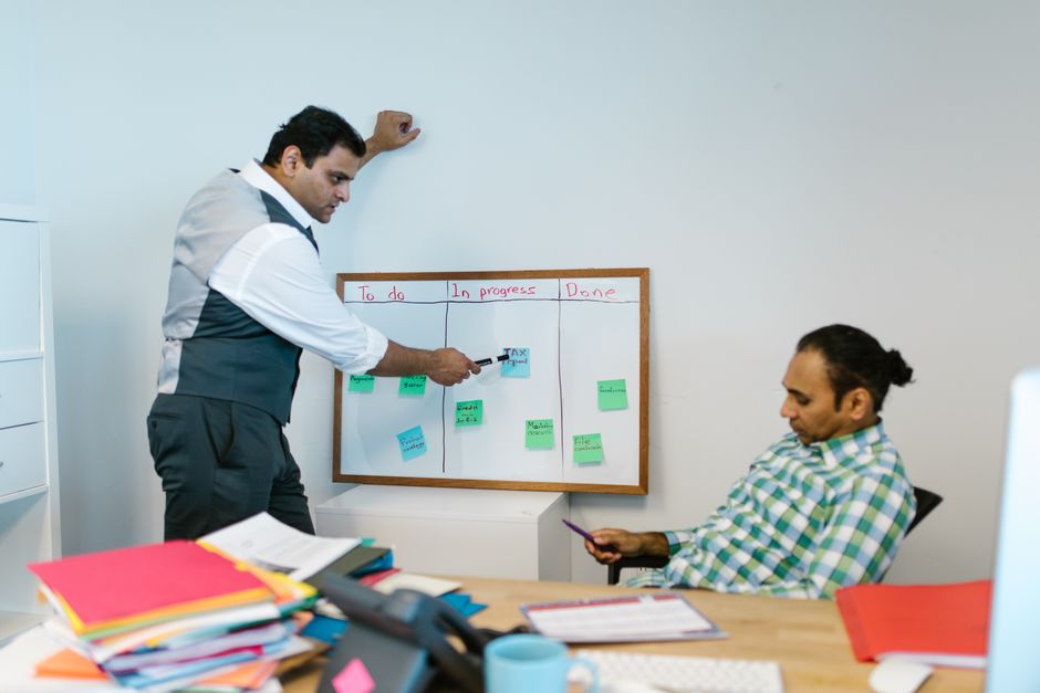 Deux hommes collaborant sur un projet devant un tableau blanc dans un bureau.