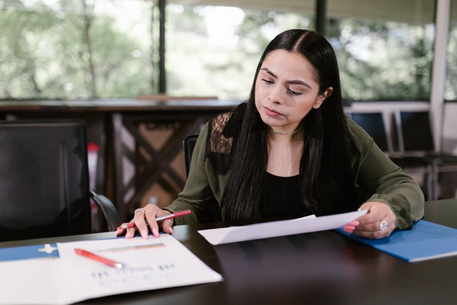 Femme professionnelle étudiant des documents avec concentration dans un bureau.