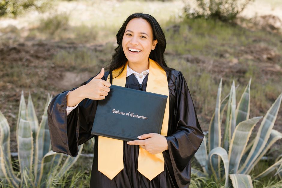 Étudiante diplômée joyeuse tenant son diplôme lors d'une célébration en extérieur.