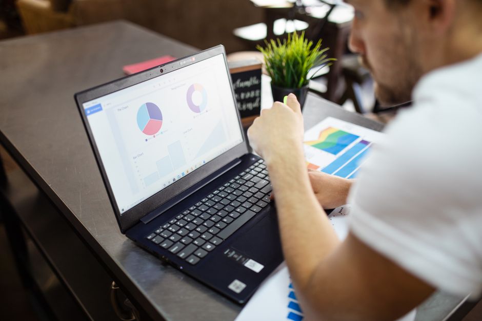 Homme examinant des tableaux et des graphiques sur un ordinateur portable pour une analyse commerciale.
