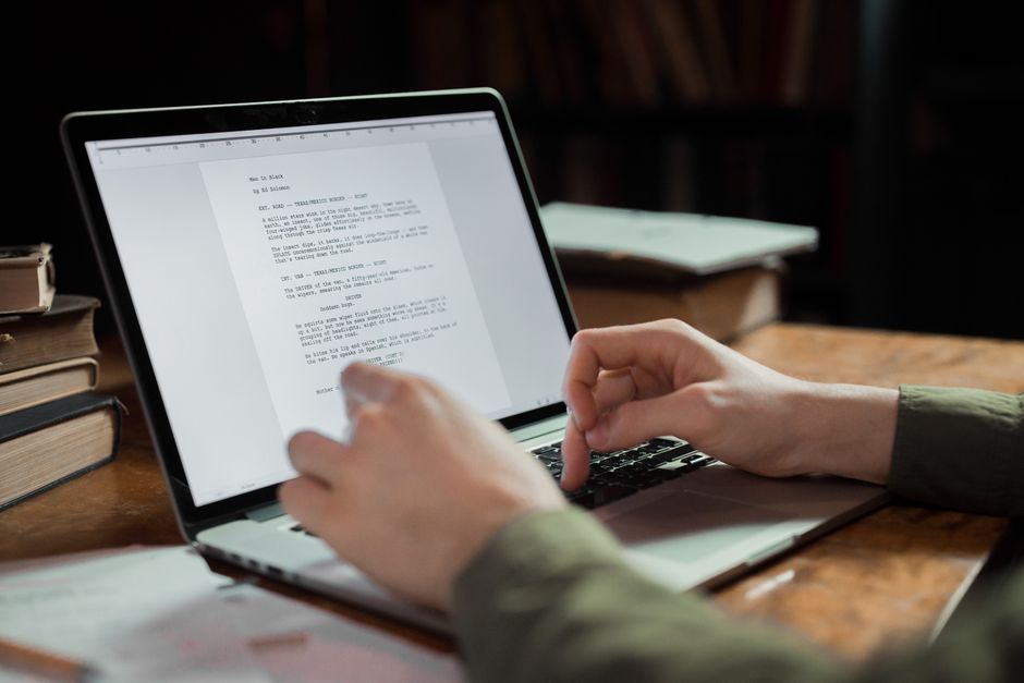 Une personne qui tape sur un ordinateur portable dans un espace de travail confortable entouré de livres, idéal pour les thèmes de l'écriture et de la technologie.