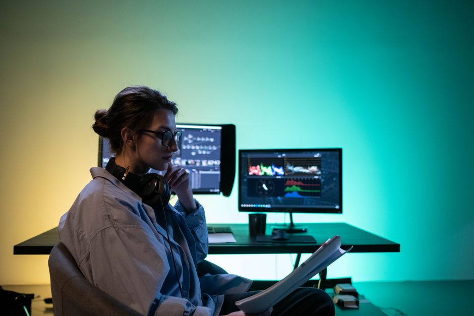 Femme montant une vidéo sur un bureau moderne équipé de deux écrans dans un bureau.