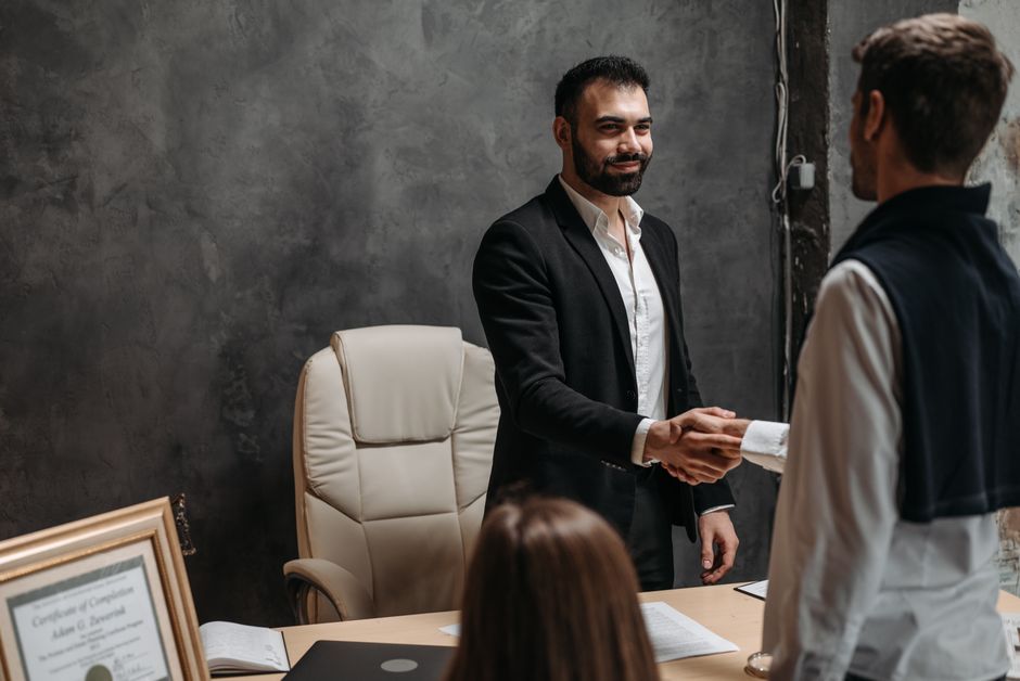 Hommes d'affaires en costume se serrant la main dans un bureau professionnel.
