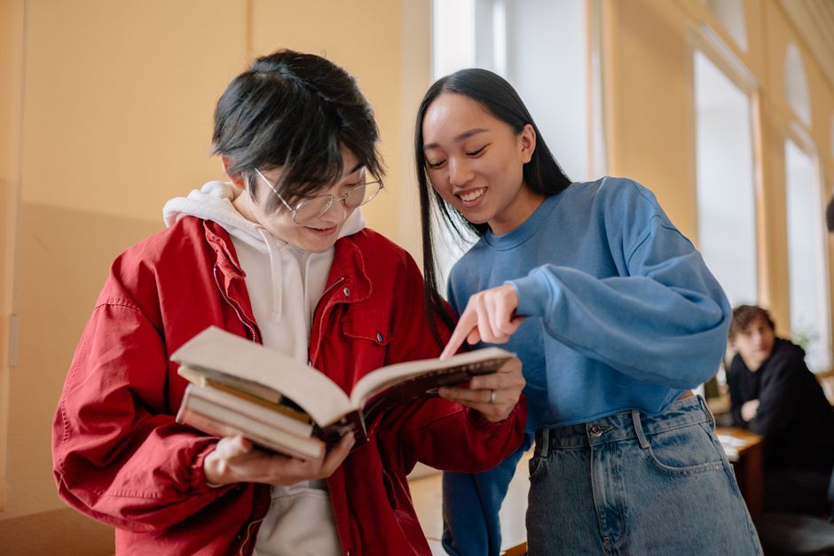Jeunes étudiants collaborant et souriant tout en étudiant ensemble dans un couloir d'université.