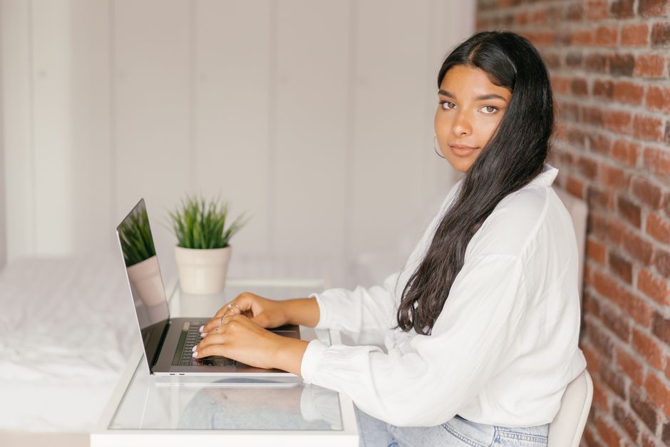 Jeune femme assise à un bureau travaillant sur un ordinateur portable dans son espace de travail à domicile.