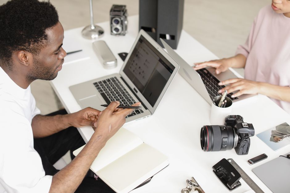 Photographes collaborant dans un espace de travail moderne avec des appareils photo et des ordinateurs portables.
